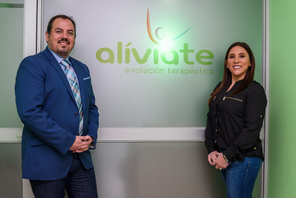 Cristian Bello y Brisa Sandoval, cofundadores de Alíviate, junto al logo del centro en Concepción
